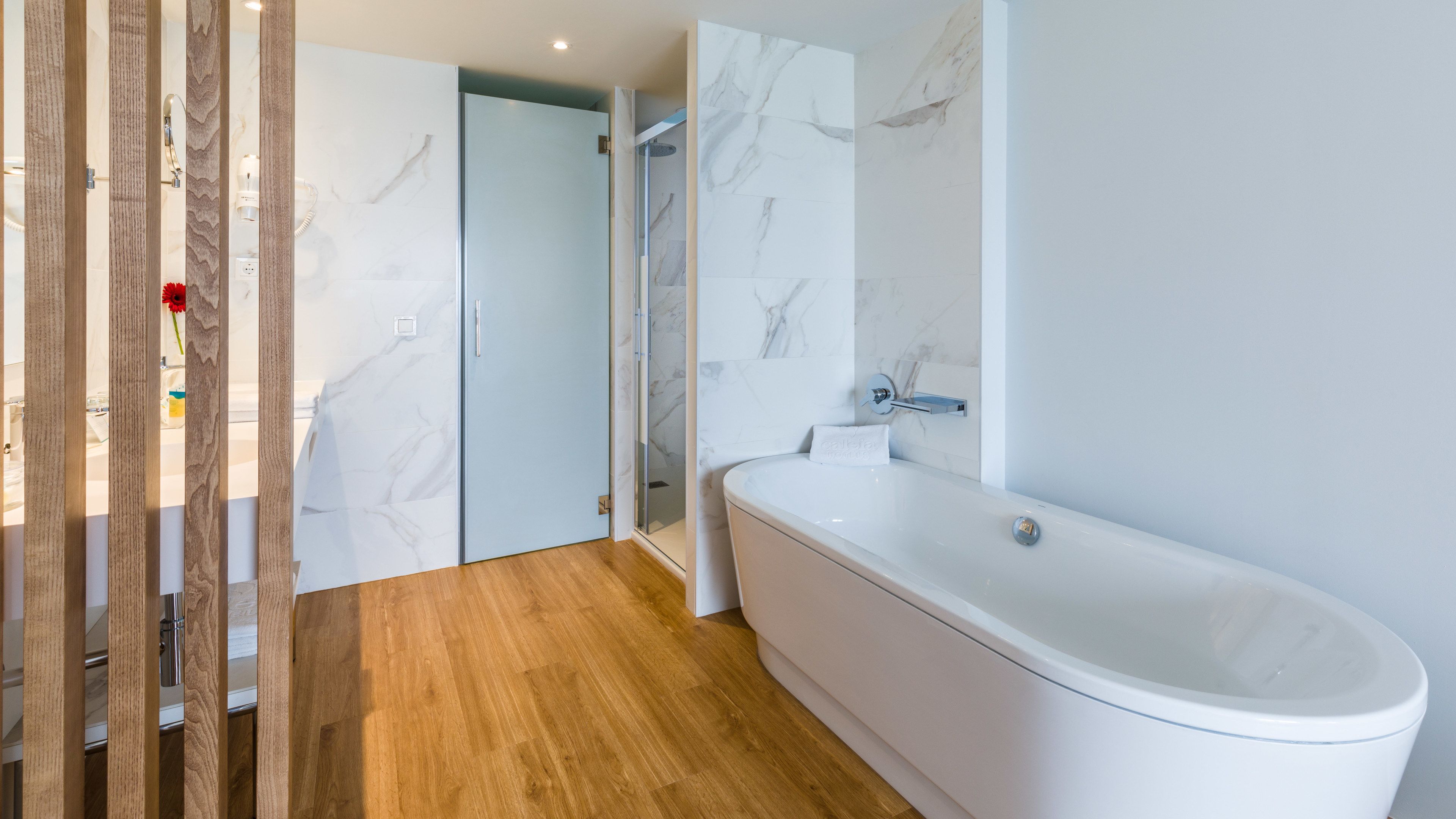 Une salle de bain moderne avec une baignoire sur pieds, un espace douche et un plancher en bois.