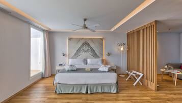 A modern bedroom with a large bed, a ceiling fan, a marble artwork, and a wooden partition.