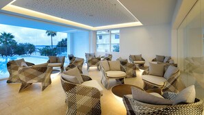 Un salón moderno con mobiliario de mimbre, ventanas amplias y vistas a la piscina.