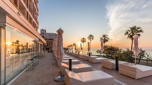A rooftop terrace with seating areas, palm trees, and a view of the sunset. - Talayot Hotel by Senator - Adults Only (Son Servera)