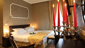 Ein Hotelzimmer mit Bett, Nachttisch, Lampe und einem Kerzenleuchter mit Kerzen.