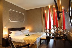 A hotel room with a bed, bedside table, lamp, and a candelabra with candles.