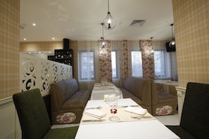 A dining area with two sofas, a table set for two, and a chandelier.