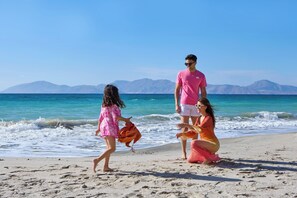 På stranden, solsenger, parasoller og sandvolleyball