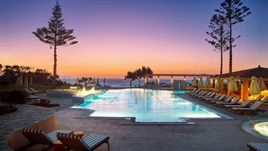A pool area with lounge chairs and umbrellas, overlooking the ocean at sunset. - Zeus Kos Beach (Kos)