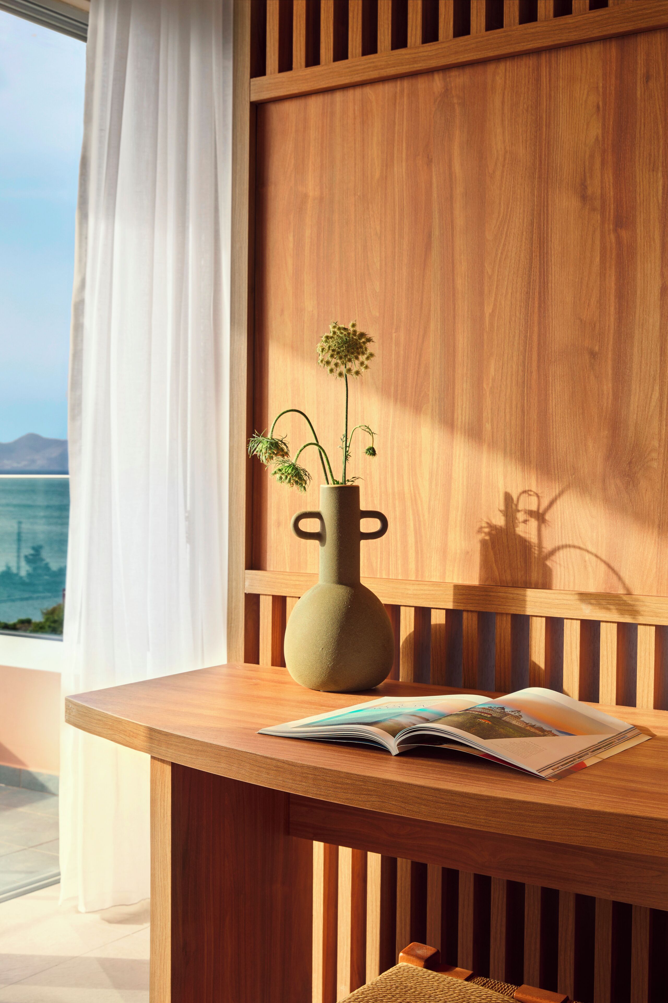 Ein Holztisch mit einer Blumenvase und einer geöffneten Zeitschrift.