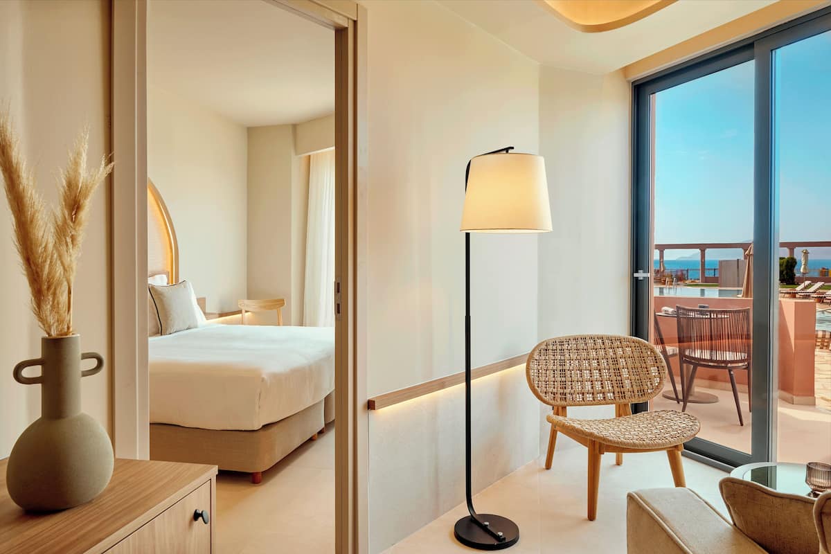 Una habitación de hotel moderna con cama, lámpara de pie, silla de mimbre y vistas al balcón.