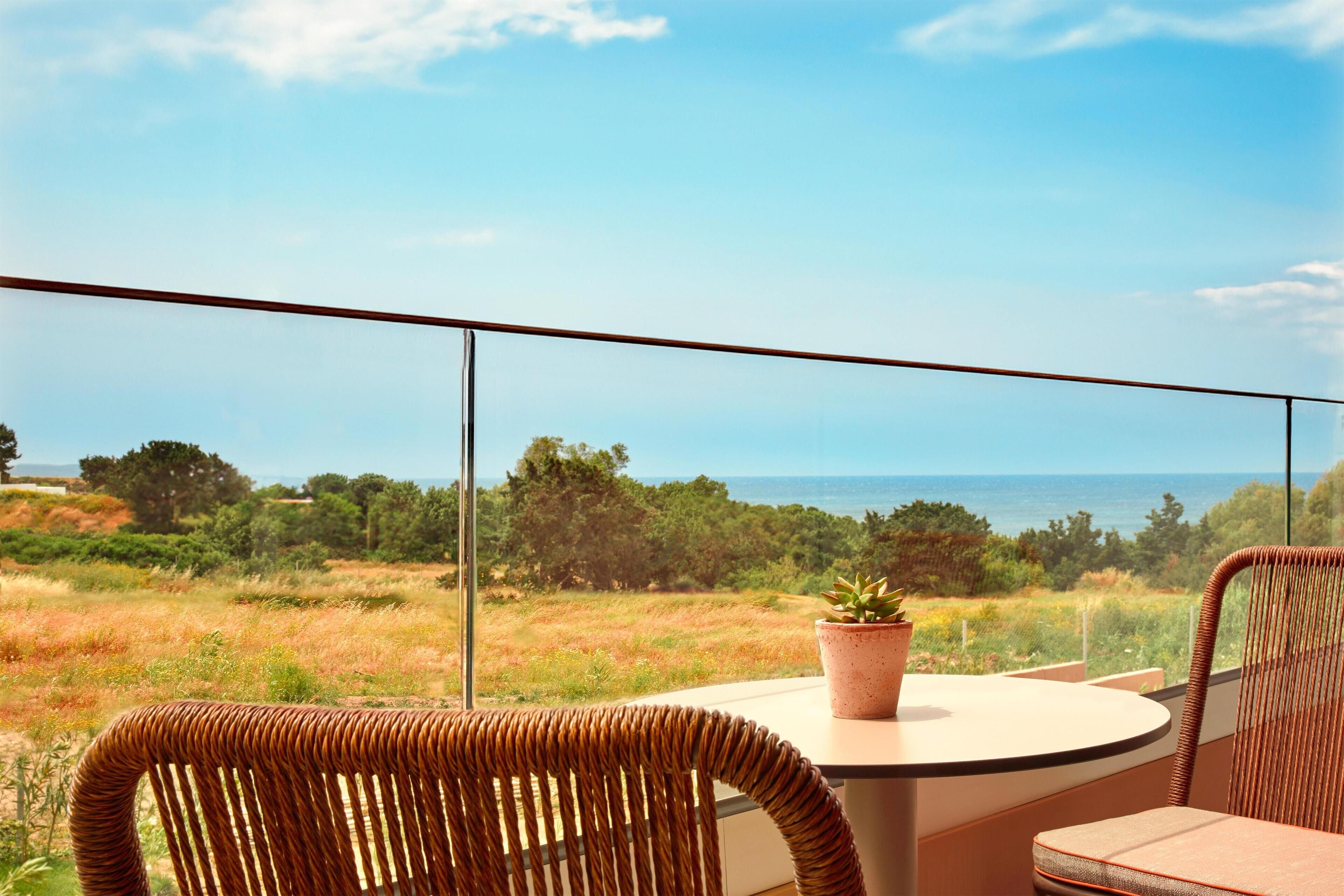 A balcony with wicker chairs, a table, and a potted plant.