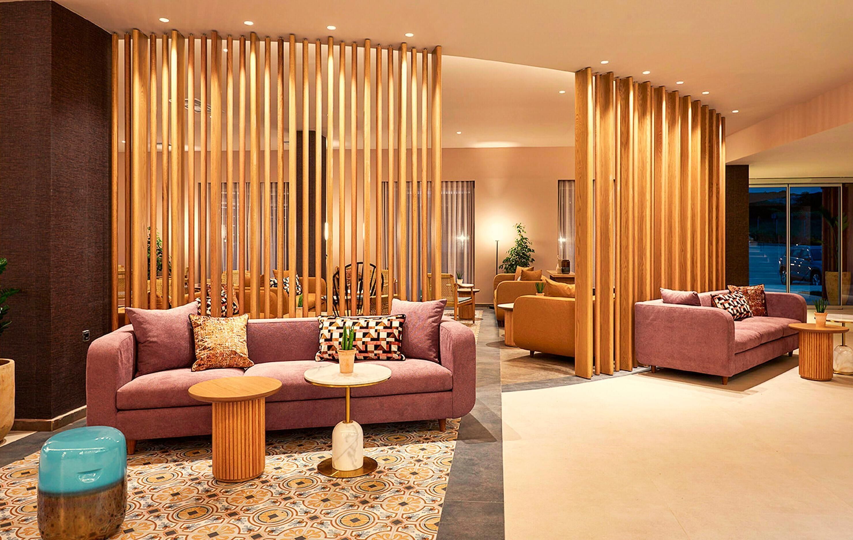 A modern lobby with a pink sofa, wooden partitions, and a patterned floor.