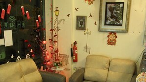 A living room with two sofas, a small table with a vase, and a decorative wall with a framed picture and a fire extinguisher. - Putra One Avenue Hotel (Seri Kembangan)
