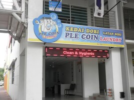 Une laverie avec une enseigne indiquant « PLE COIN LAUNDRY » et un écran numérique affichant : « Propre et hygiénique ».