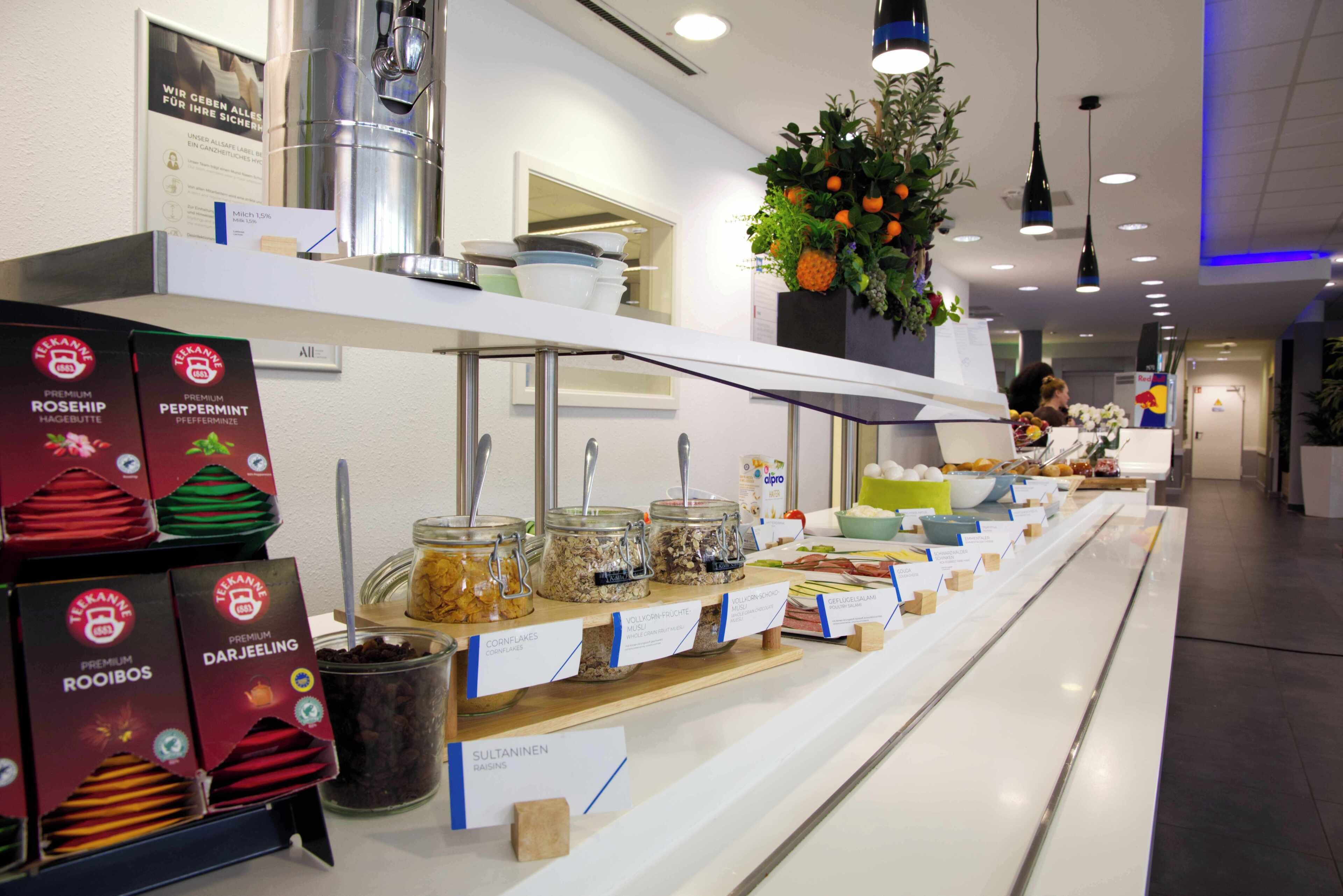 Zona de bufé con diversas opciones de comida y bebidas, incluyendo cajas de tés premium y una variedad de platos presentados en un mostrador.