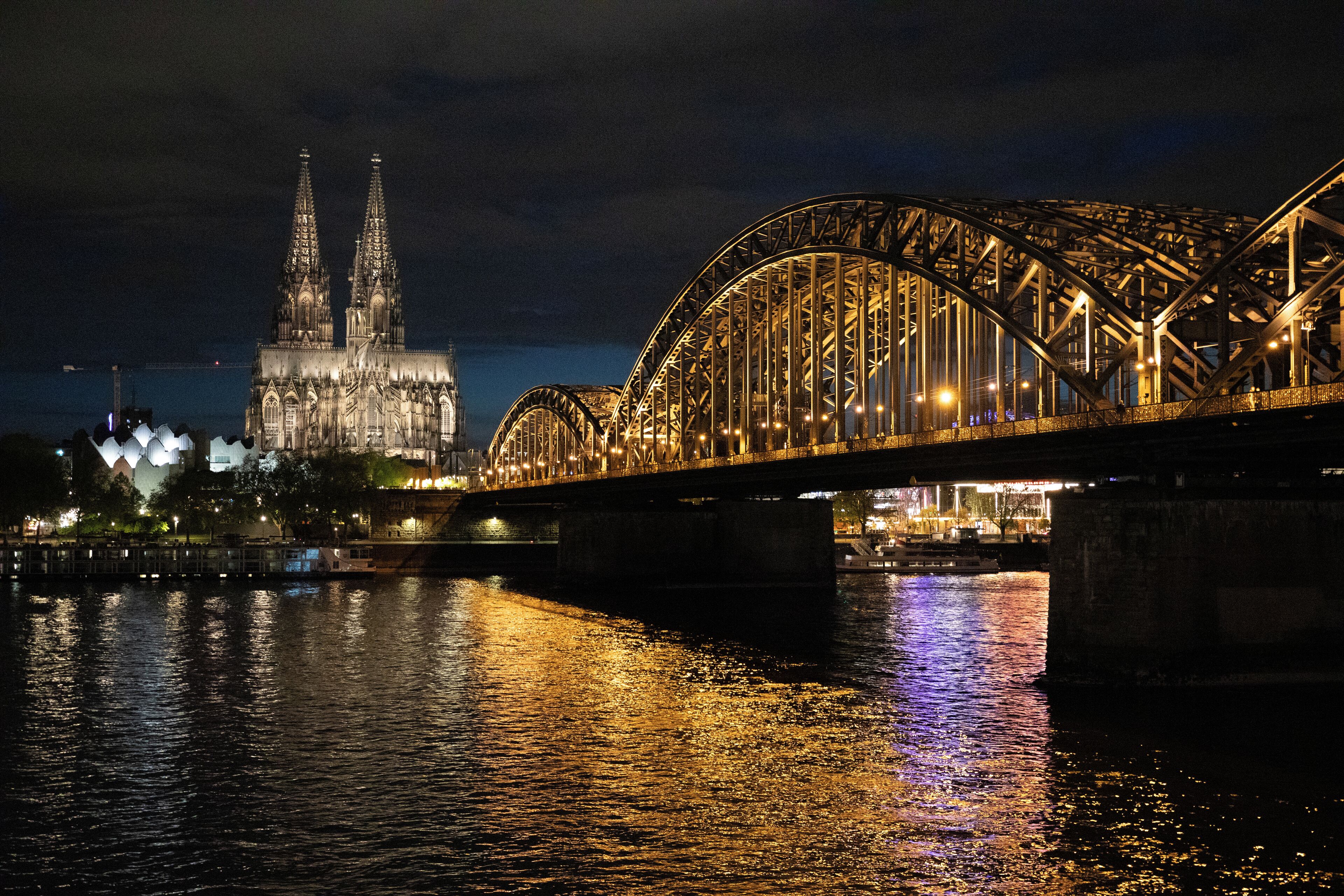 A nighttime view of a bridge with a cathedral in the background.