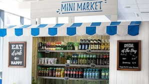 En kiosk med et udvalg af drikkevarer og snacks, en tavle med dagens tilbud, og et skilt der siger "EAT drink be happy".