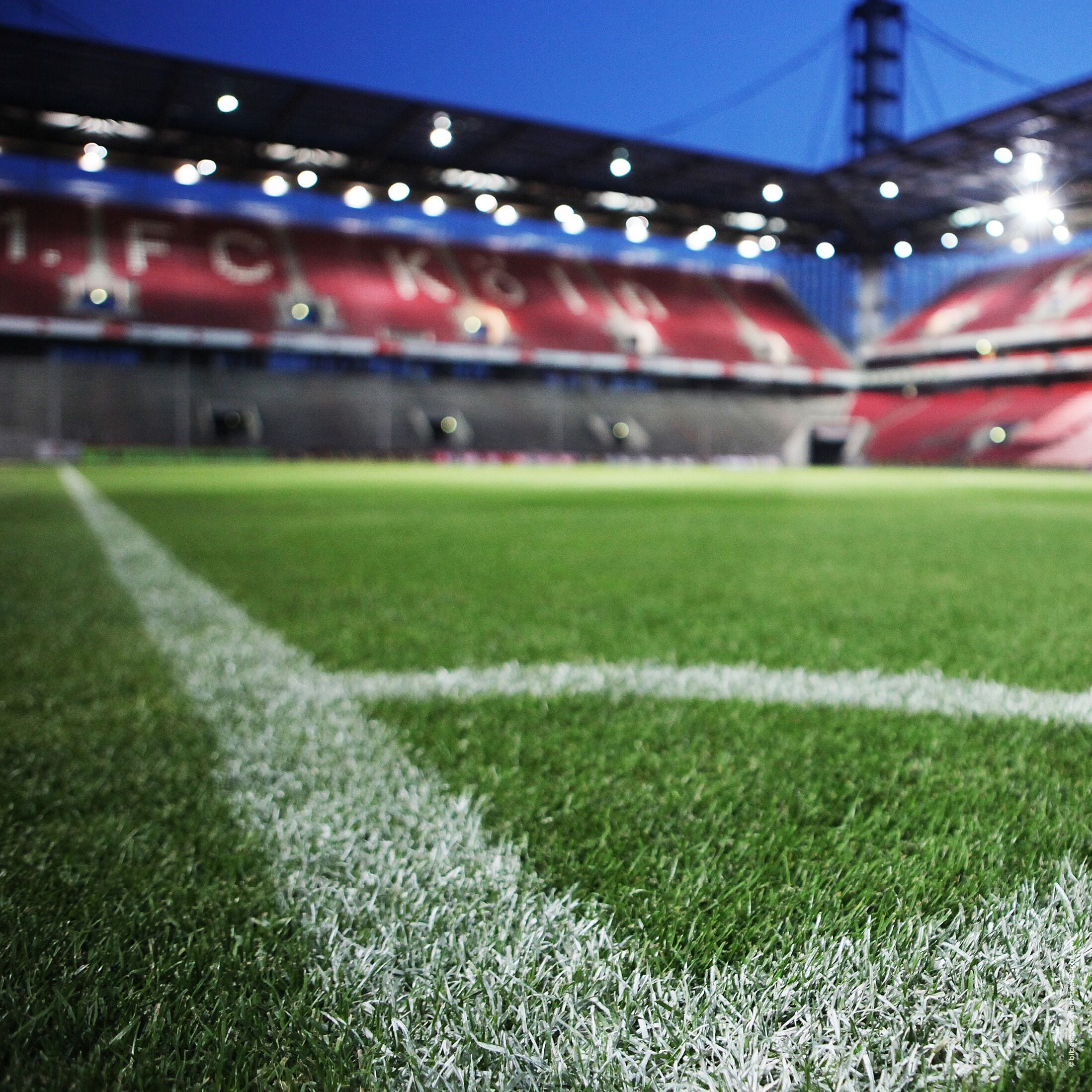 Un estadio de fútbol con césped en buen estado y asientos para el público.