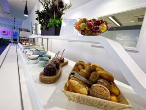 Ein Buffet mit verschiedenen Brotsorten, Marmeladen und einer Obstschale.