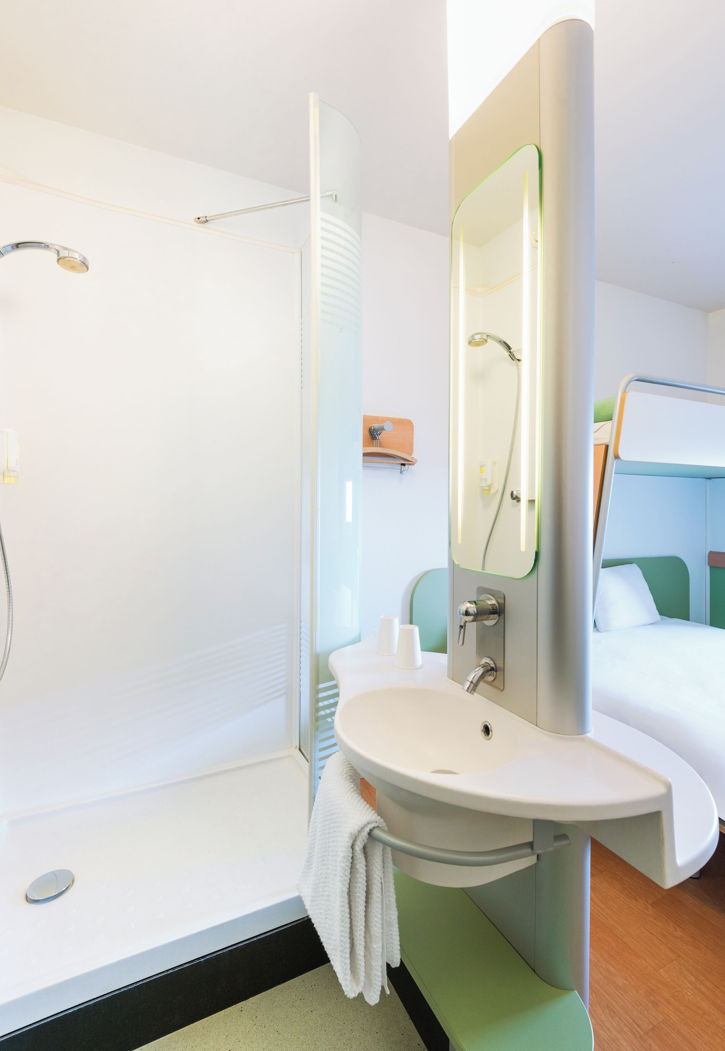 A modern bathroom with a glass-enclosed shower, a sink with a towel, and a mirror.