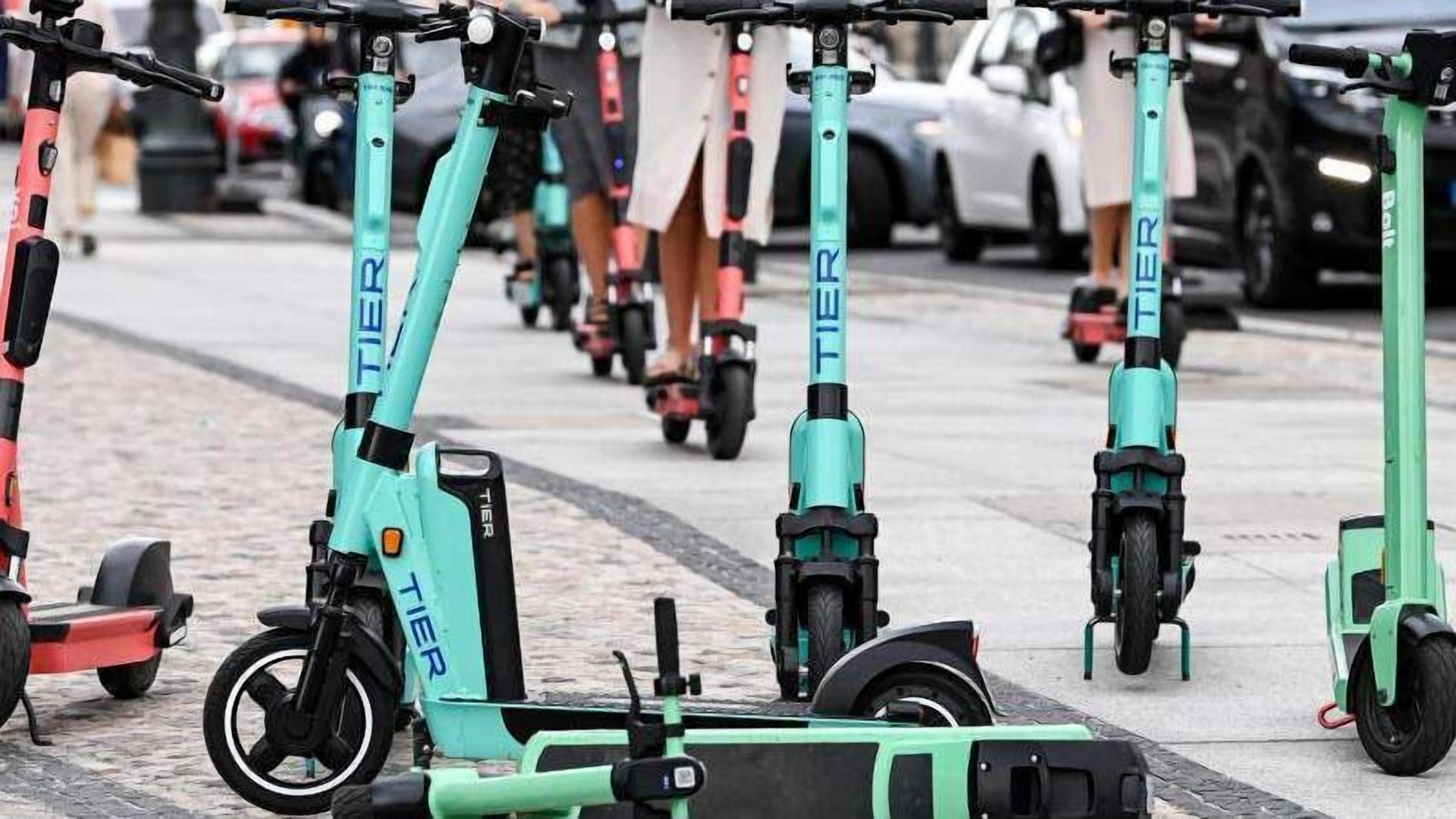 A row of electric scooters parked on a sidewalk.