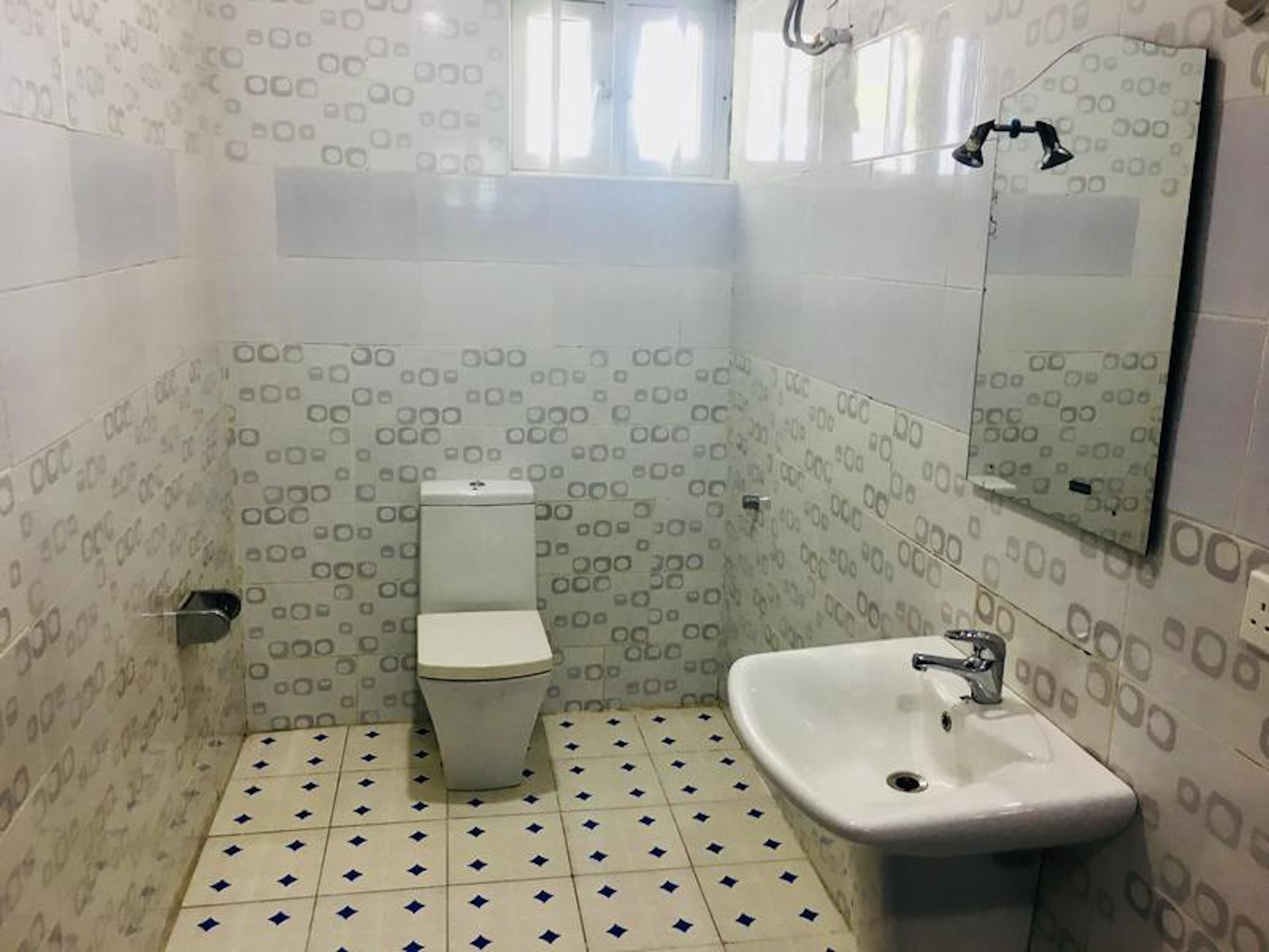 Un baño con inodoro, lavamanos y espejo.