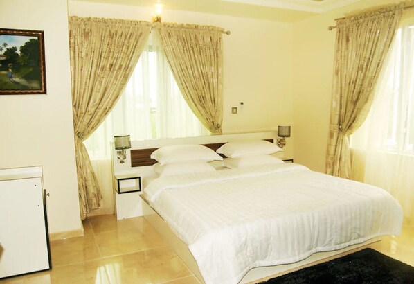 A bedroom with a bed, nightstands, and curtains.