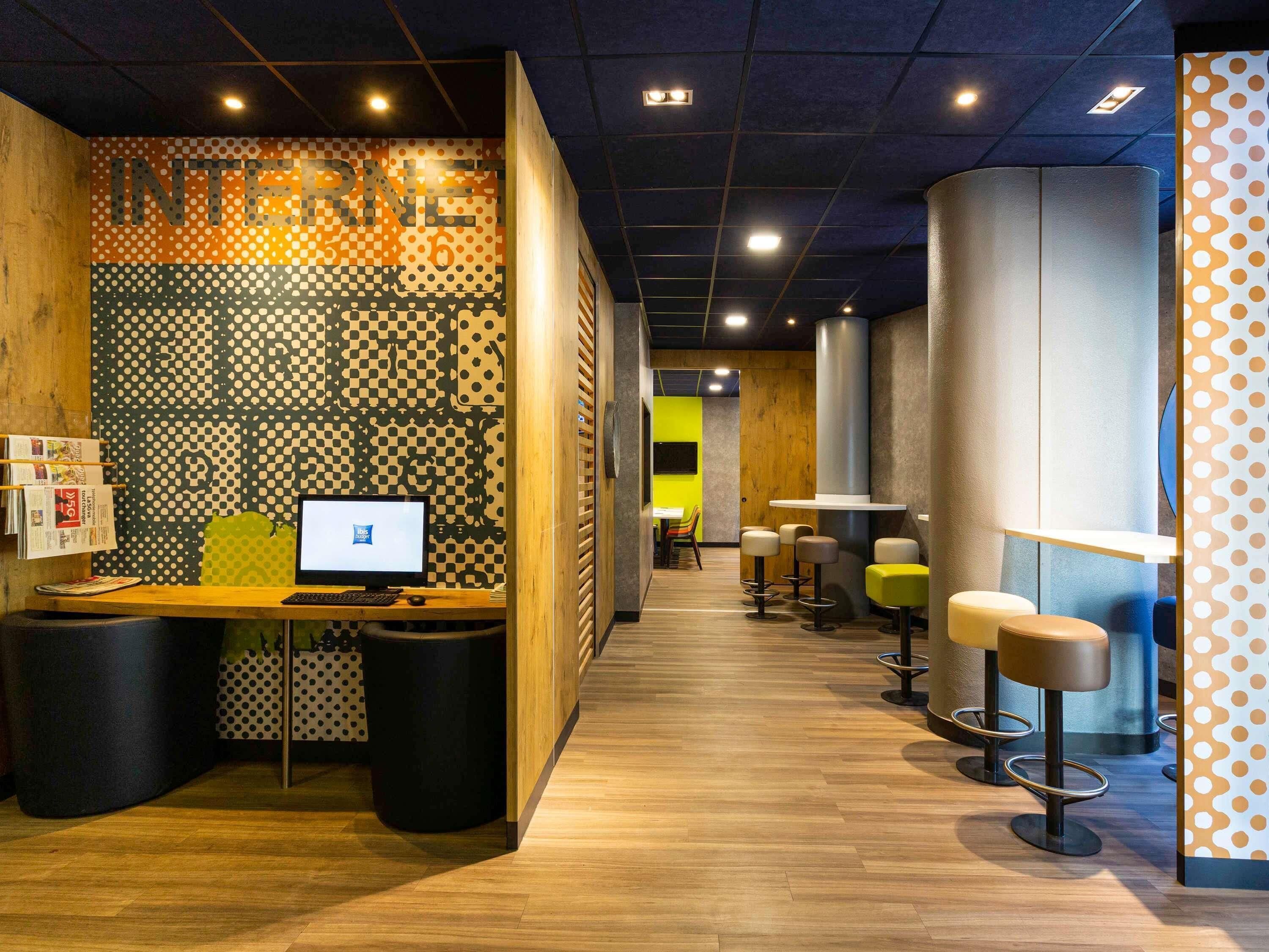 Un interior moderno con mostrador de recepción, computadora y taburetes de bar.