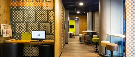 Un interior moderno con mostrador de recepción, computadora y taburetes de bar.