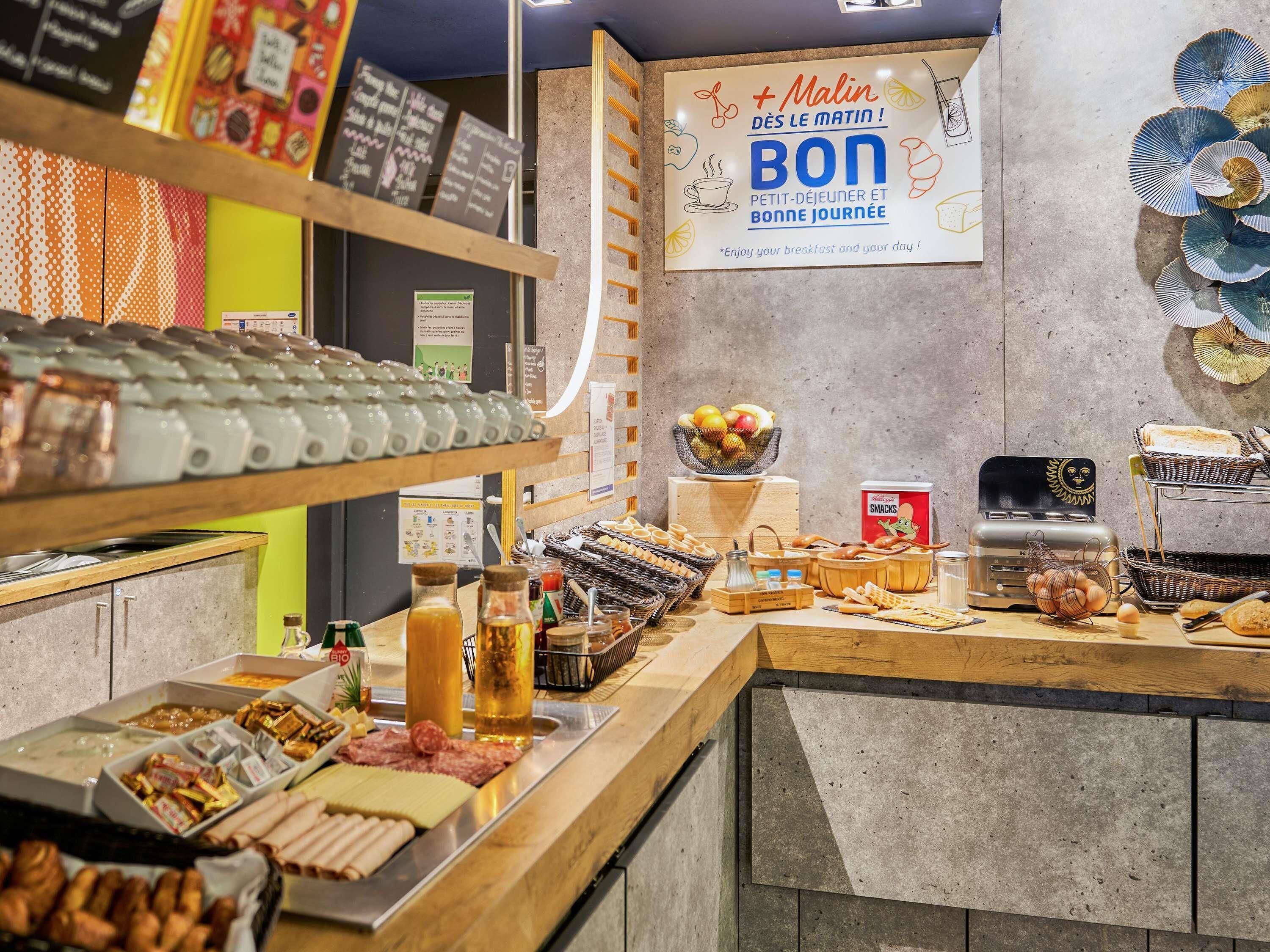 A breakfast buffet with various food items and a sign that reads 'MALIN DESS LE MATIN! BON PETIT-DÉJEUNER ET BONNE JOURNÉE.'