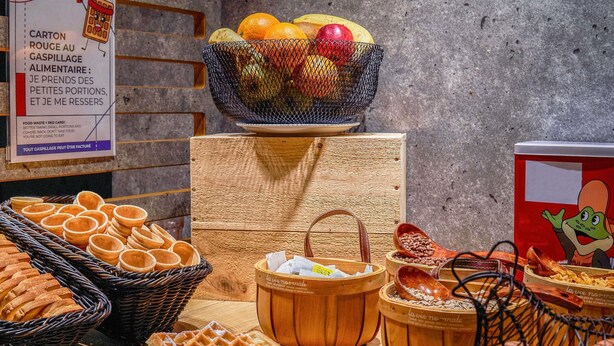 A buffet with various food items including waffles, bread, and a fruit bowl. - ibis budget Bordeaux Centre Gare Saint Jean (Bordeaux)