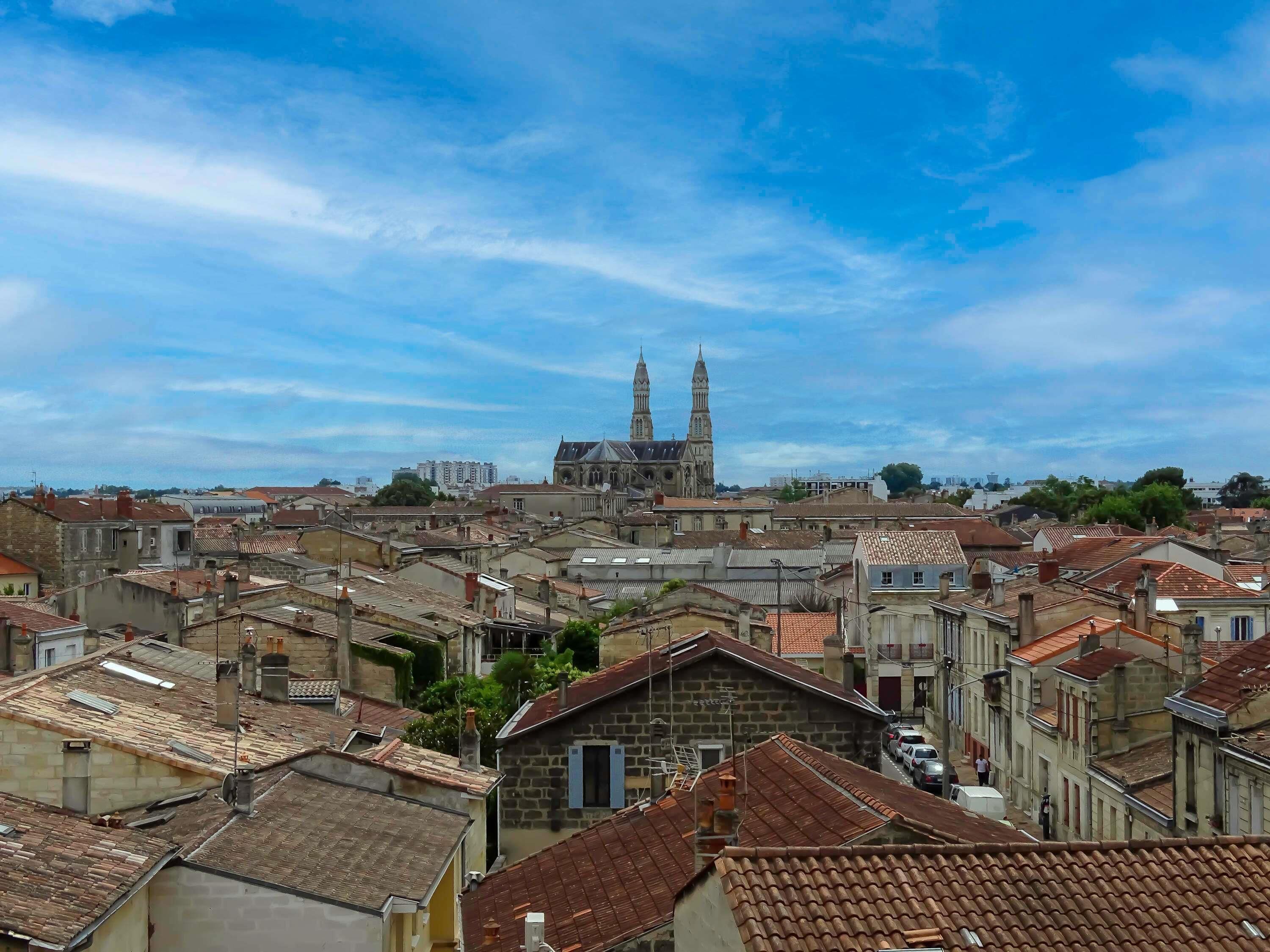 A historic cityscape with dense urban buildings, a prominent church with twin spires, and a clear sky.