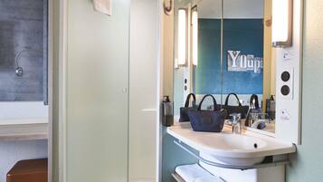 A modern bathroom with a glass shower enclosure, a sink with a vanity, and a mirror with a 'You' sign.