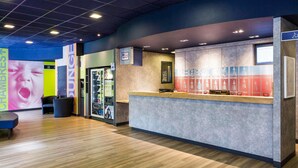 A reception area with a counter, seating, and a vending machine. - ibis budget Bordeaux Centre Gare Saint Jean (Bordeaux)