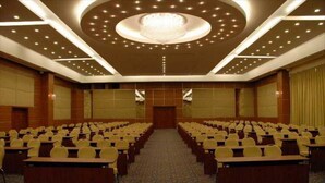 A conference room with rows of tables and chairs, a chandelier, and a carpeted floor. - Sealight Resort Hotel (Kusadasi)