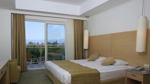 A hotel room with a large bed, a desk, a chair, and a view of the outdoors through a sliding door. - Sealight Resort Hotel (Kusadasi)