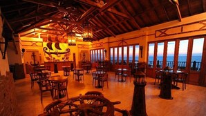 A nautical-themed restaurant with wooden tables and chairs, large windows overlooking the sea, and a warm, wooden interior. - Sealight Resort Hotel (Kusadasi)