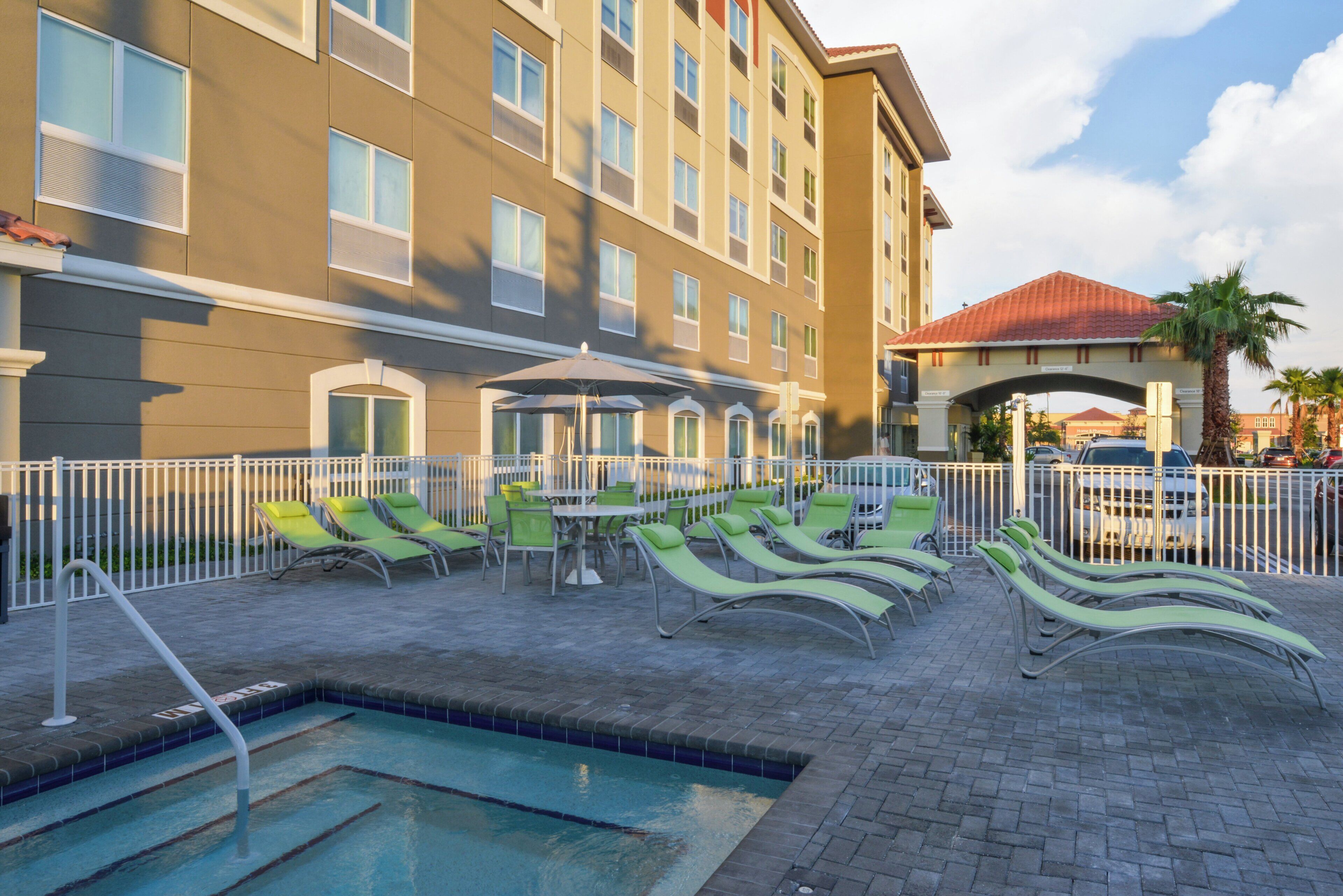 A hotel pool area with lounge chairs and a pool.