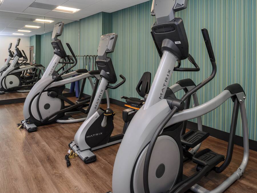 Eine Reihe von Steh- oder Heimtrainer in einem Fitnessstudio mit Holzboden und Wänden mit grünen Streifen.