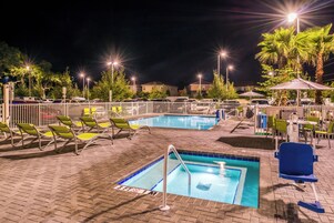 Una piscina al aire libre, sombrillas, sillones reclinables de piscina