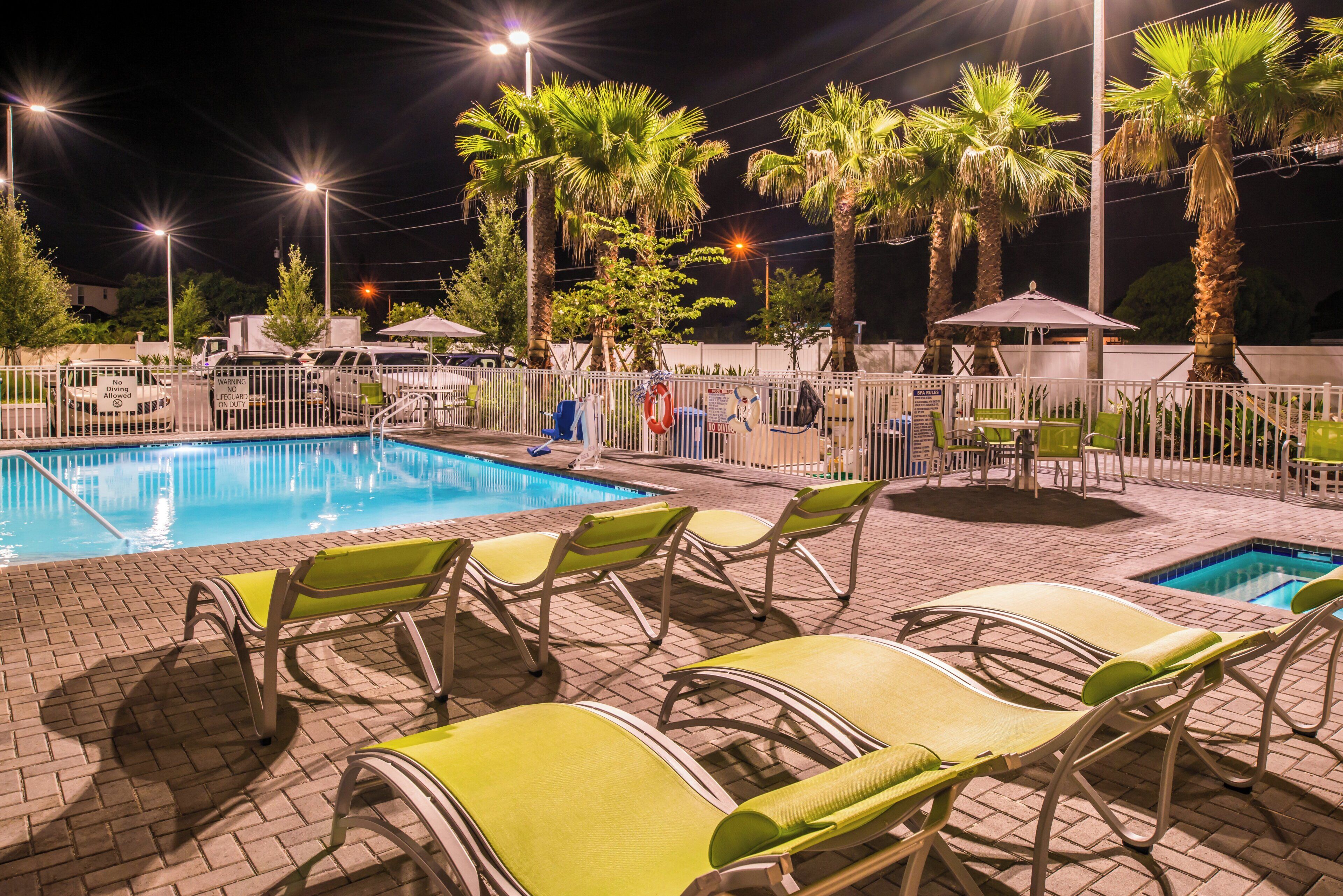 A swimming pool area with lounge chairs and palm trees.