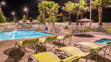 A swimming pool area with lounge chairs and palm trees.
