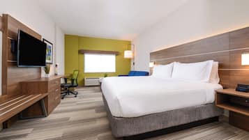 A hotel room with a bed, desk, chair, television, and a window.