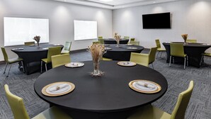 A conference room with round tables, yellow chairs, and black tablecloths. - Holiday Inn Express & Suites St. Petersburg - Madeira Beach by IHG (St. Petersburg)