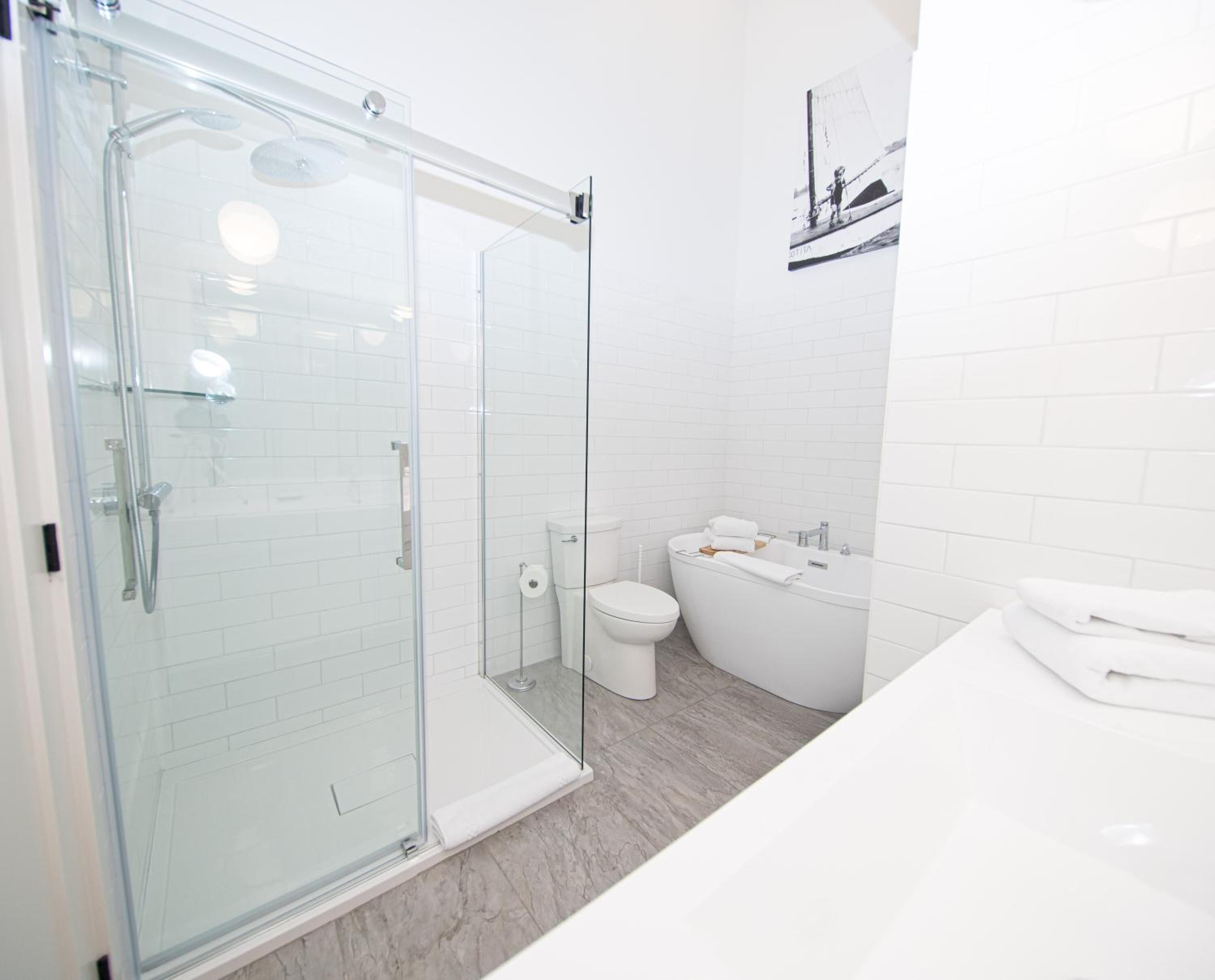 A modern bathroom with a glass-enclosed shower, a white toilet, and a bathtub.