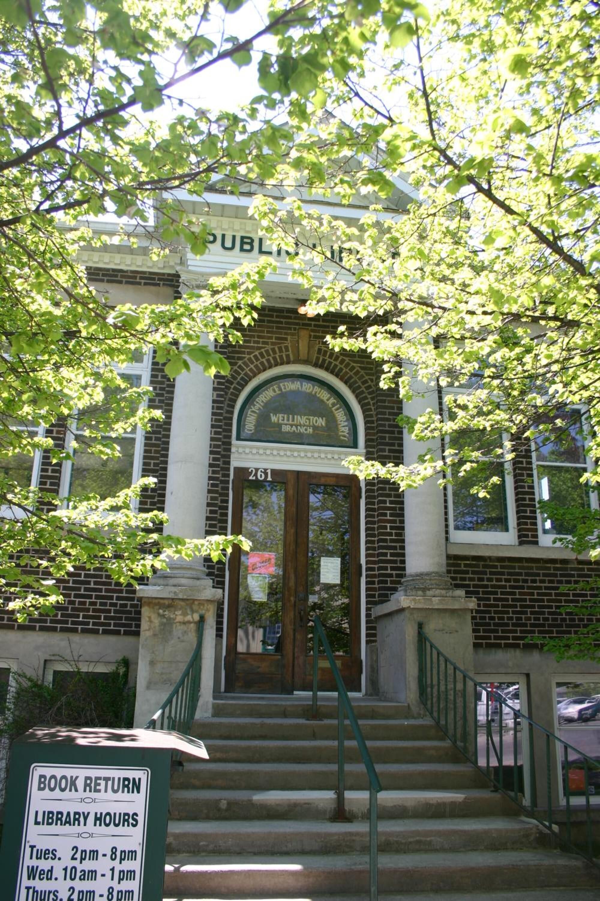 A public library entrance with a sign indicating book return and library hours.