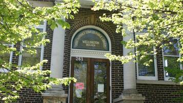 A public library entrance with a sign indicating book return and library hours.