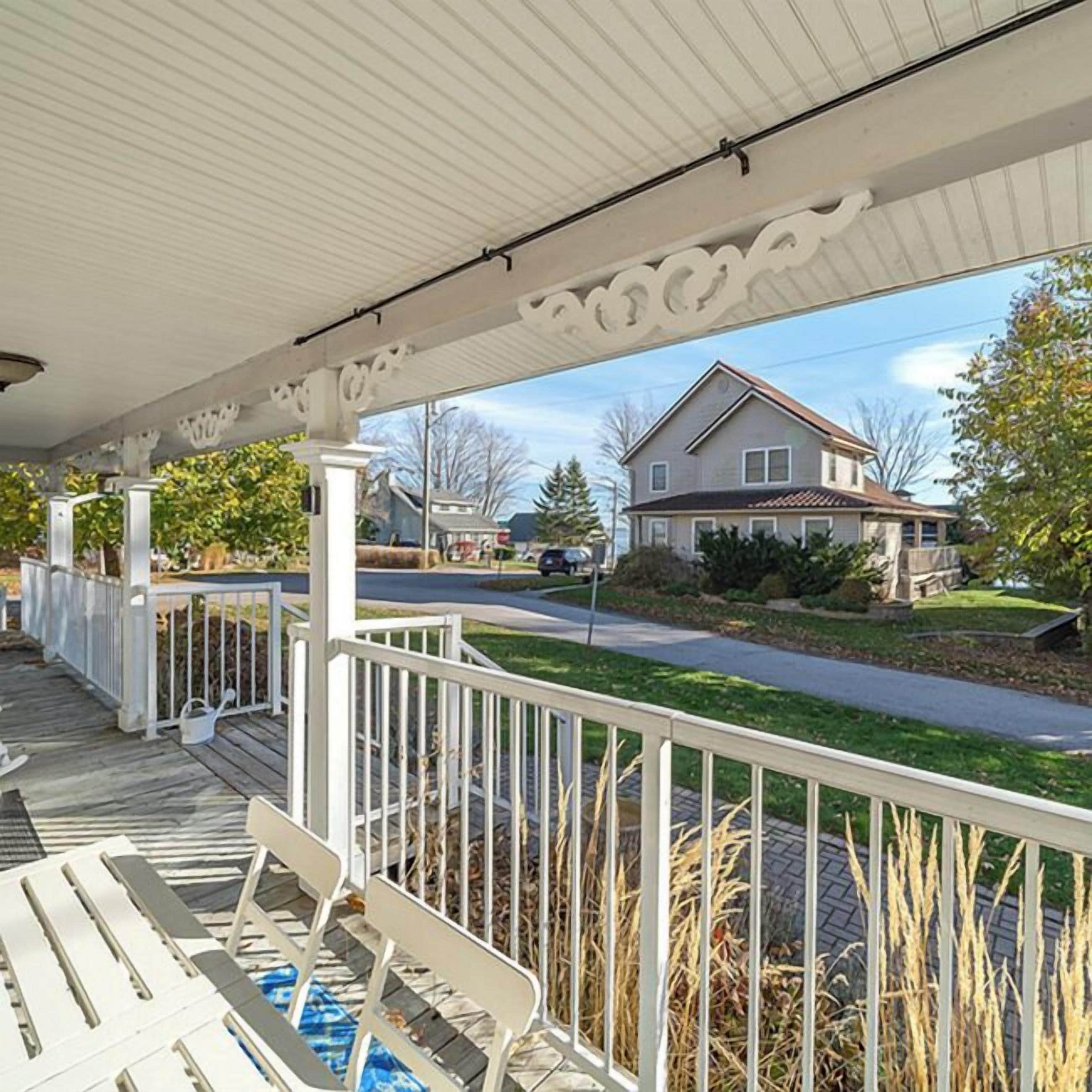 A covered porch with white railings and a view of a residential street.