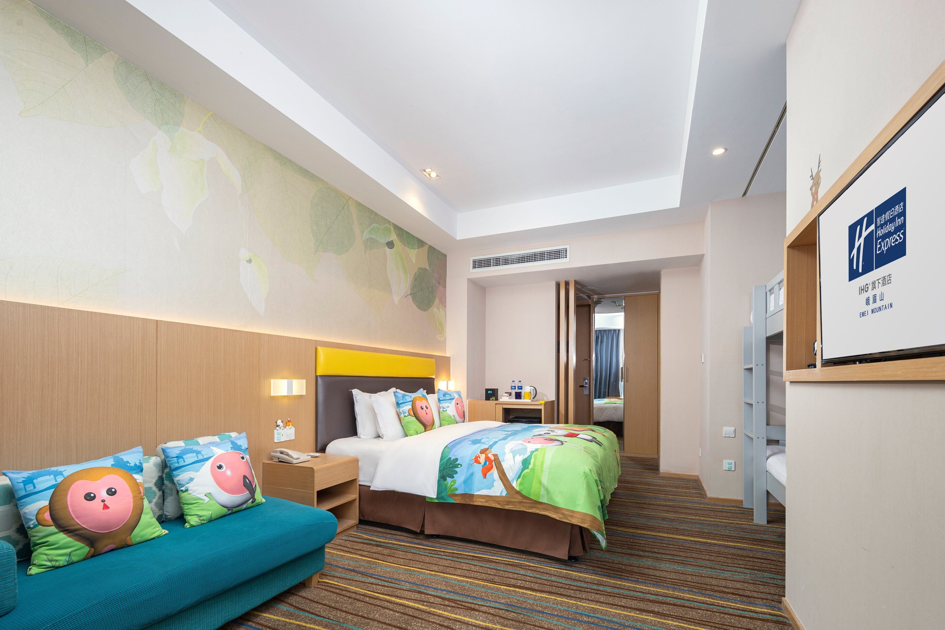 Ein Hotelzimmer mit Bett, Sofa, Schreibtisch und einem durchgegangenen Tür sichtbaren Badezimmer.