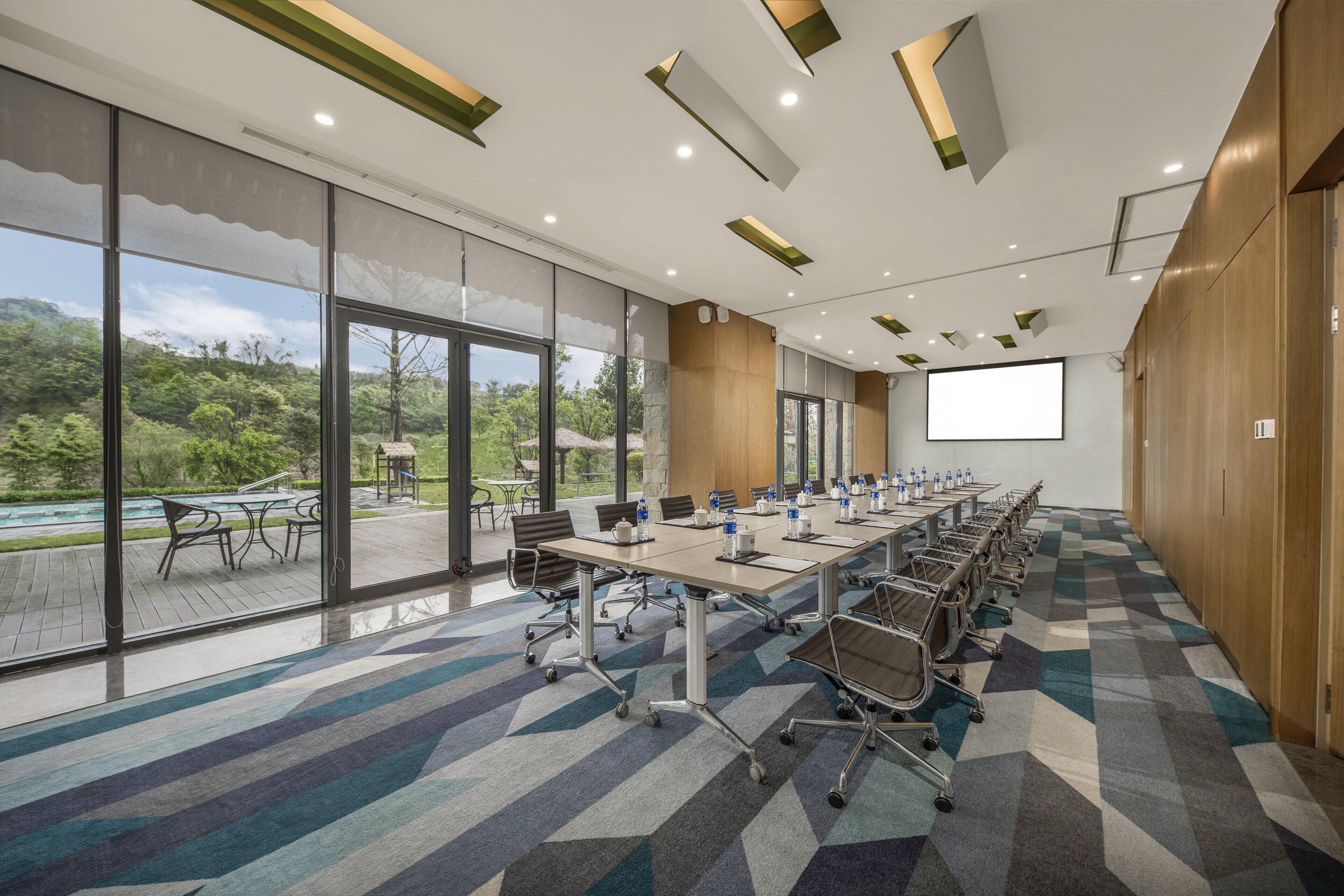 A conference room with a large table, chairs, and a projector screen.