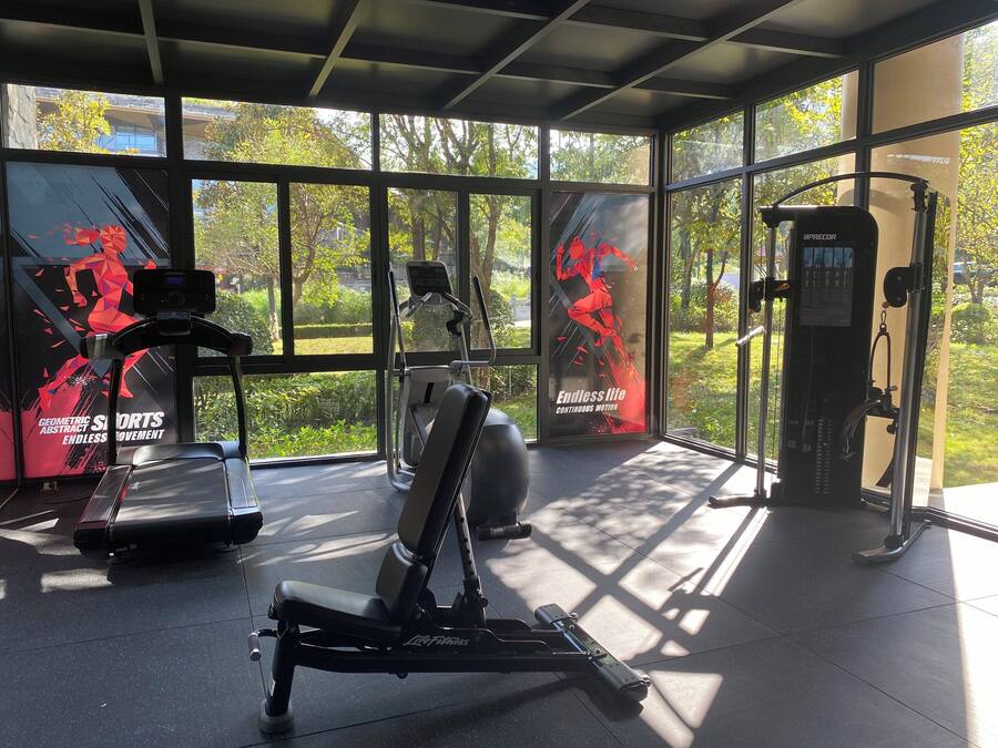 A gym with exercise equipment, large windows, and motivational posters.