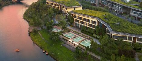 Un edificio moderno con tejados verdes, un río y un puente.