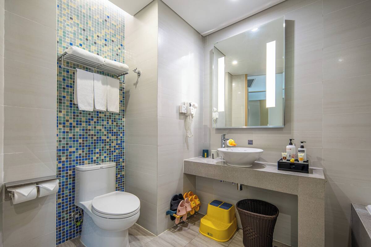 A modern bathroom with a toilet, sink, and mirror.